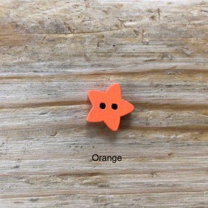 small wooden star buttons painted in different colours on wooden surface